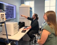 People in lab with FlowCam, pointing at screen with particle images